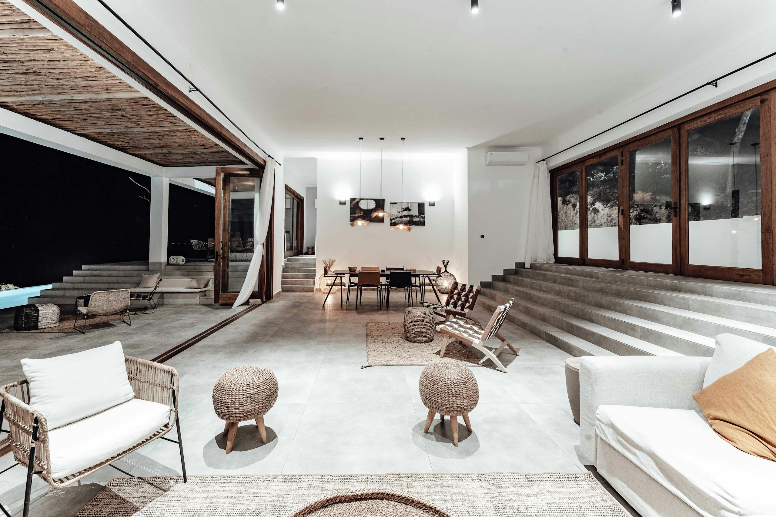 Stylish and spacious modern living area with pool view, featuring neutral decor and open design.